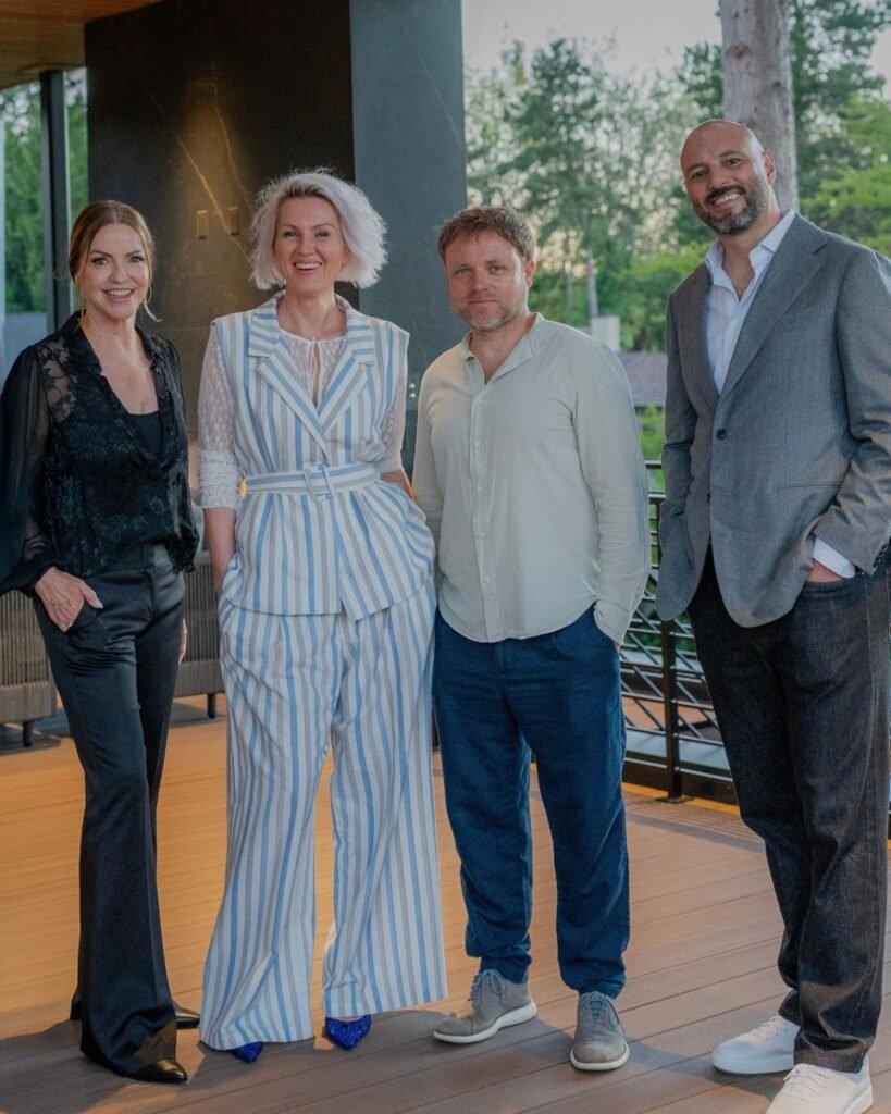 Four attendees and event partners posing together on the covered outdoor patio deck at The 8528 immersive gallery art event in Clyde Hill, Seattle.