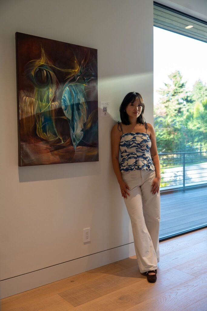 lady standing beside her contemporary abstract oil painting installation at The 8528 immersive gallery event in Clyde Hill.