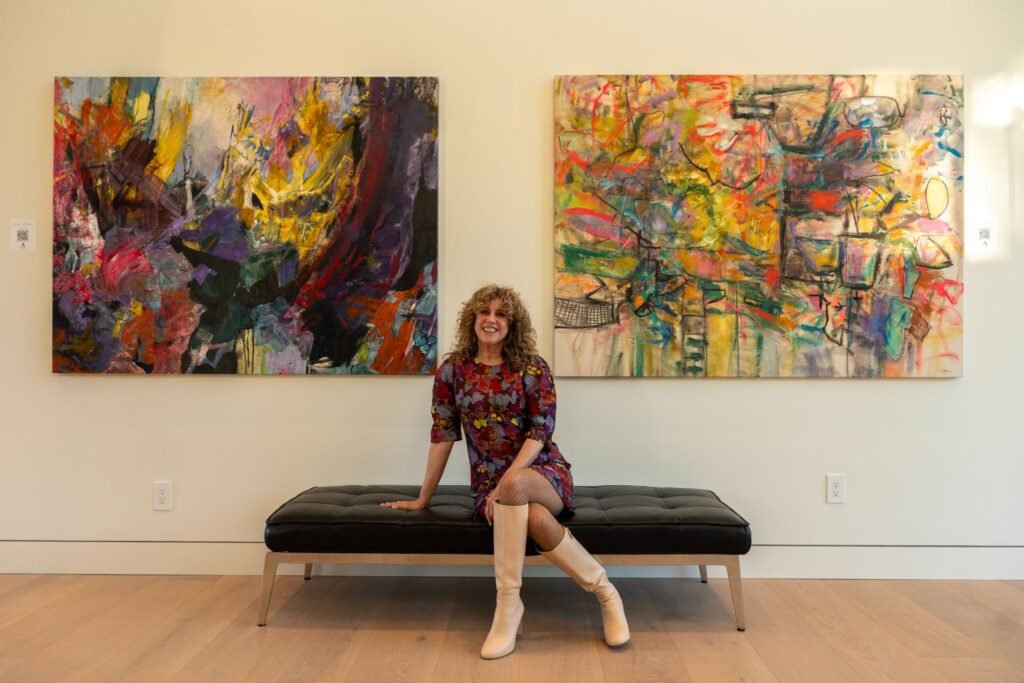 lady sitting on a black leather bench in front of vibrant abstract art installations at The 8528 immersive gallery event in Clyde Hill.