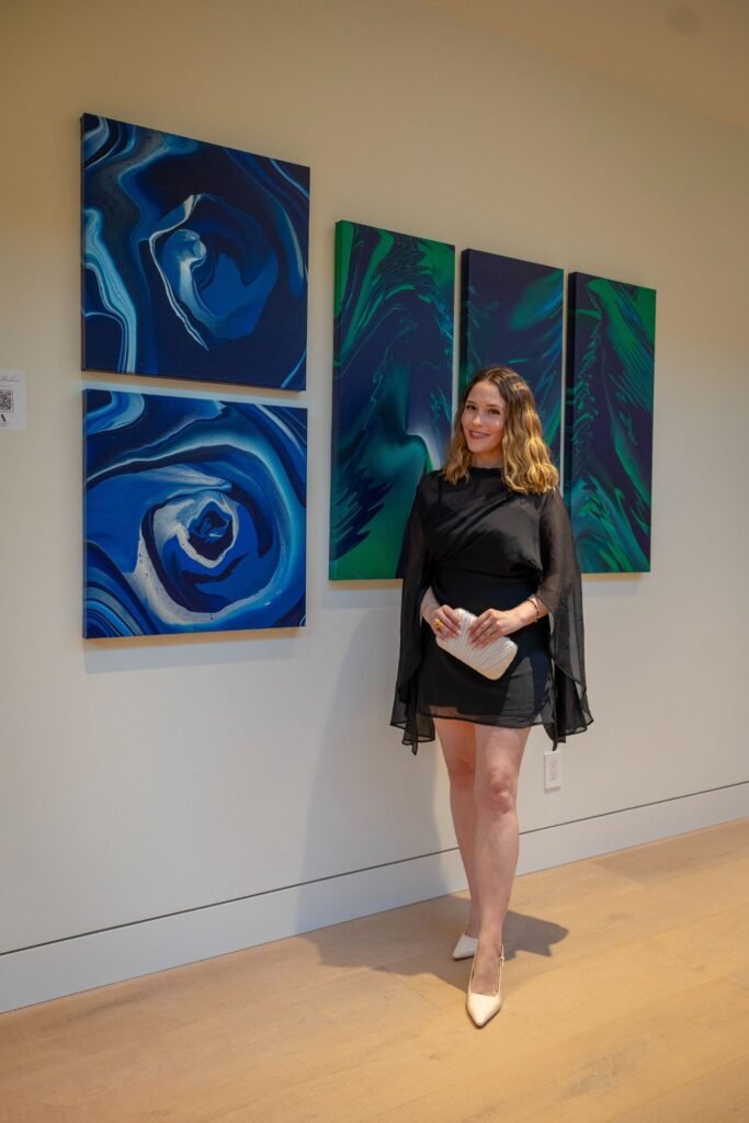 lady posing in a black dress next to contemporary blue and green abstract paintings at The 8528 immersive gallery event in Clyde Hill, Seattle.