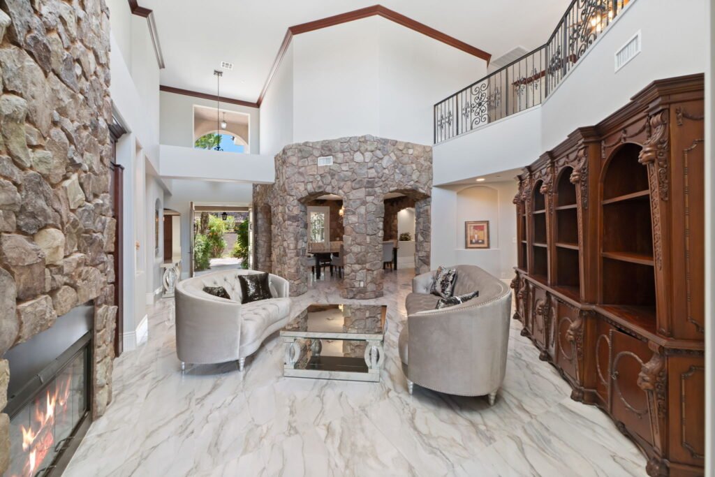 Great room inside a custom residence at 208 E Levi Avenue in Las Vegas showing high-lofted ceilings, stone accent walls, marble floors, and an upper-level wrought-iron banister balcony.