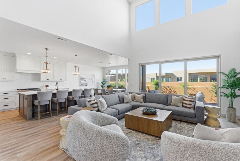 Luxury real estate interior at Tava Resort showcasing a large sectional sofa, a spacious kitchen island with barstools, and expansive sliding glass doors.