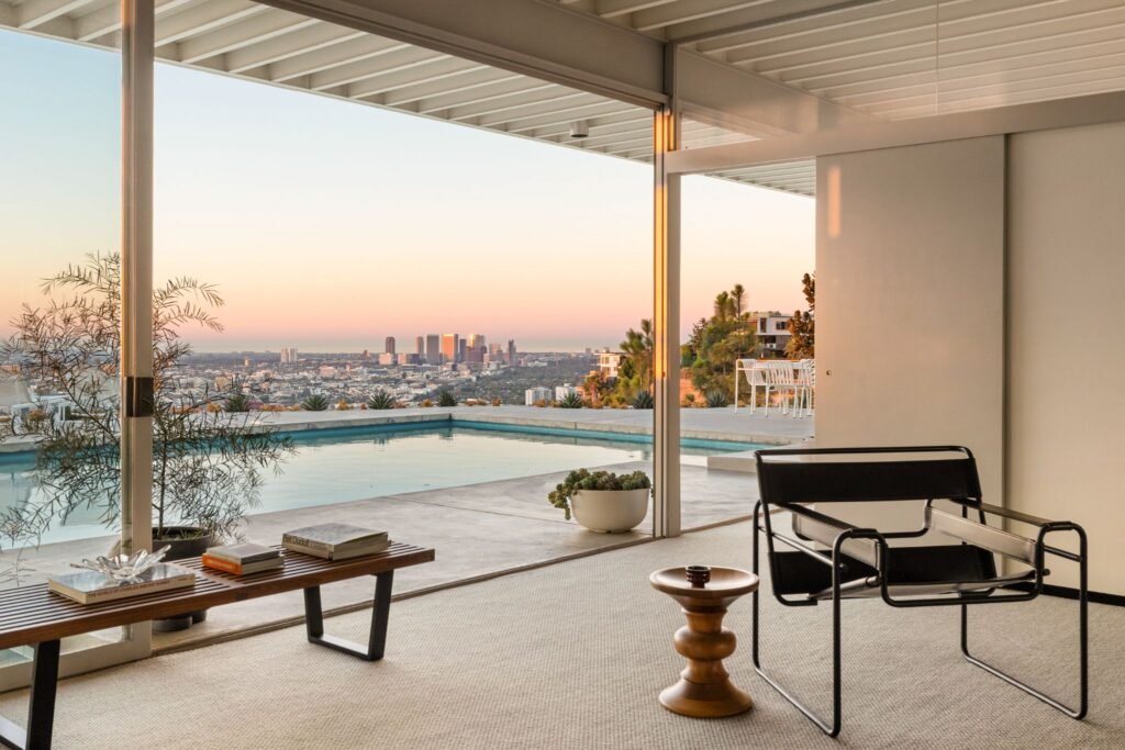 Stahl House Case Study House 22 living area at sunset featuring a Wassily chair, outdoor swimming pool, and a view of the Los Angeles skyline.