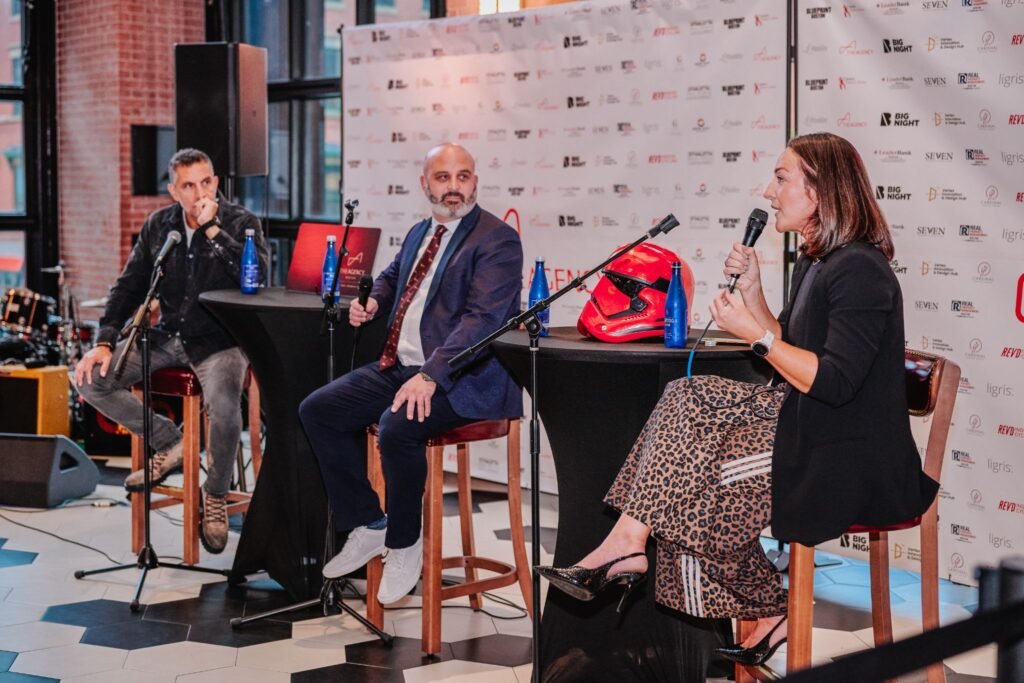 Panelist Meaghan St. Marc speaking into a microphone alongside Jamie Pollock and Mauricio Umansky during the "Building What’s Next" business panel in Boston.
