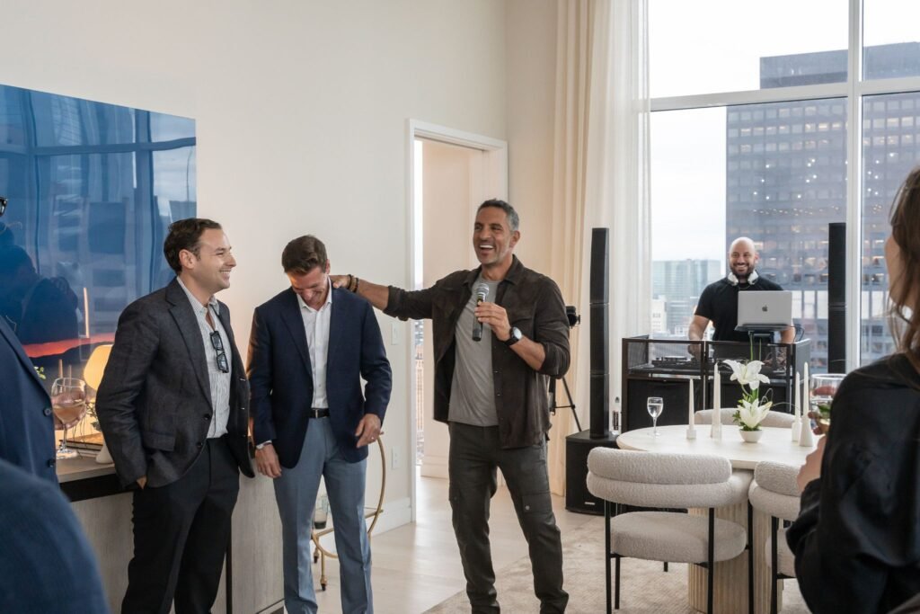 The Agency CEO Mauricio Umansky speaking into a microphone alongside agents Michael Biryla and John Antretter during the launch event for The Elysia.