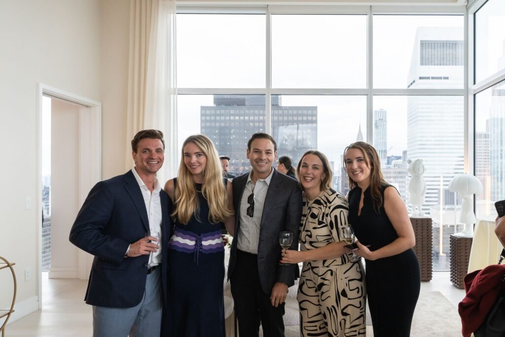 Real estate agents John Antretter and Michael Biryla posing with event guests inside Penthouse 34 at The Elysia during the Midtown Manhattan relaunch celebration.