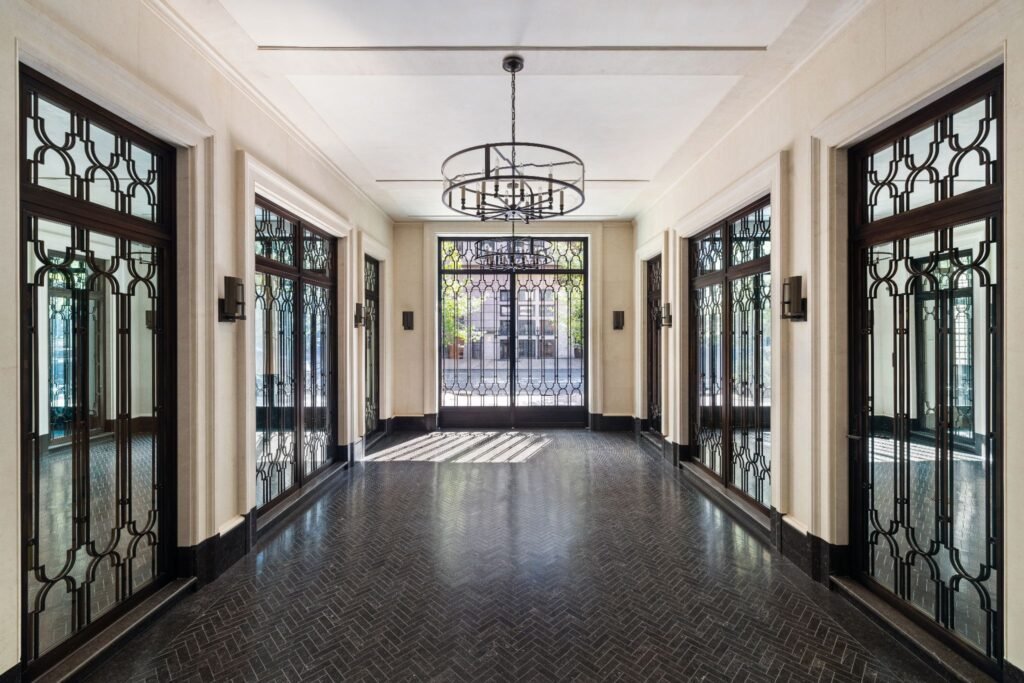 Petit Granit herringbone flooring and bronze glass doors inside the multi-functional private garage and gallery at 165 East 70th Street townhouse.