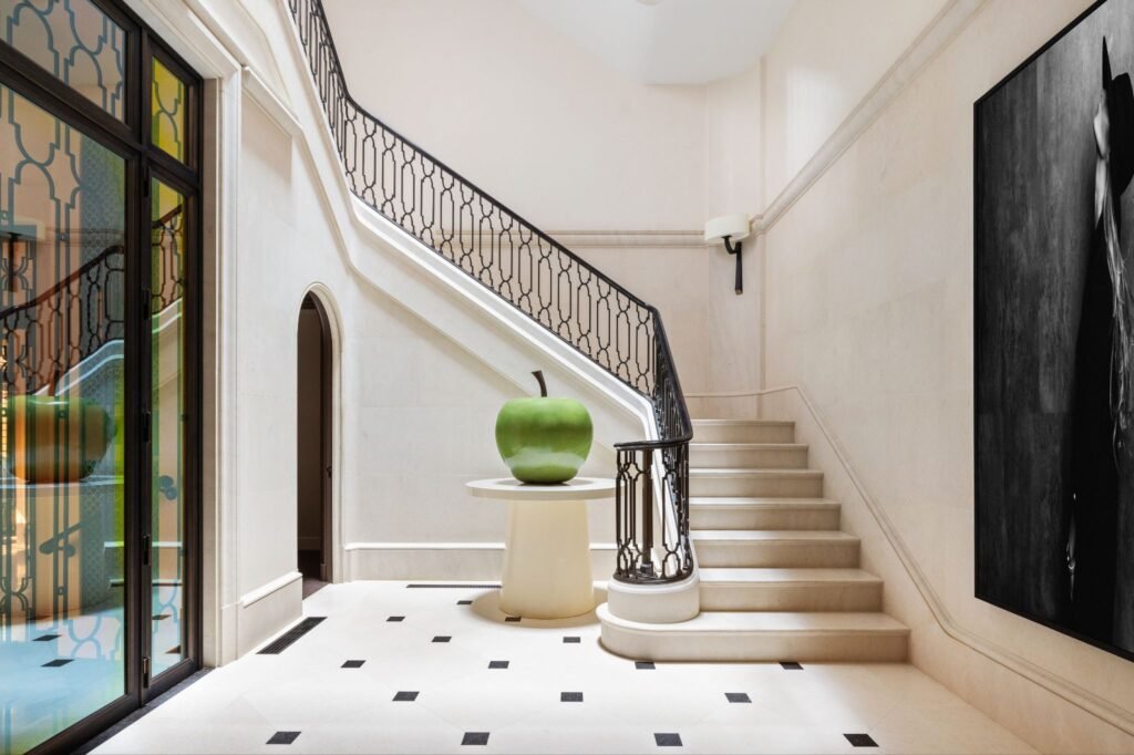 Wrought iron and limestone staircase rising through the honed Beauvallon limestone foyer at 165 East 70th Street, a luxury Upper East Side townhouse.