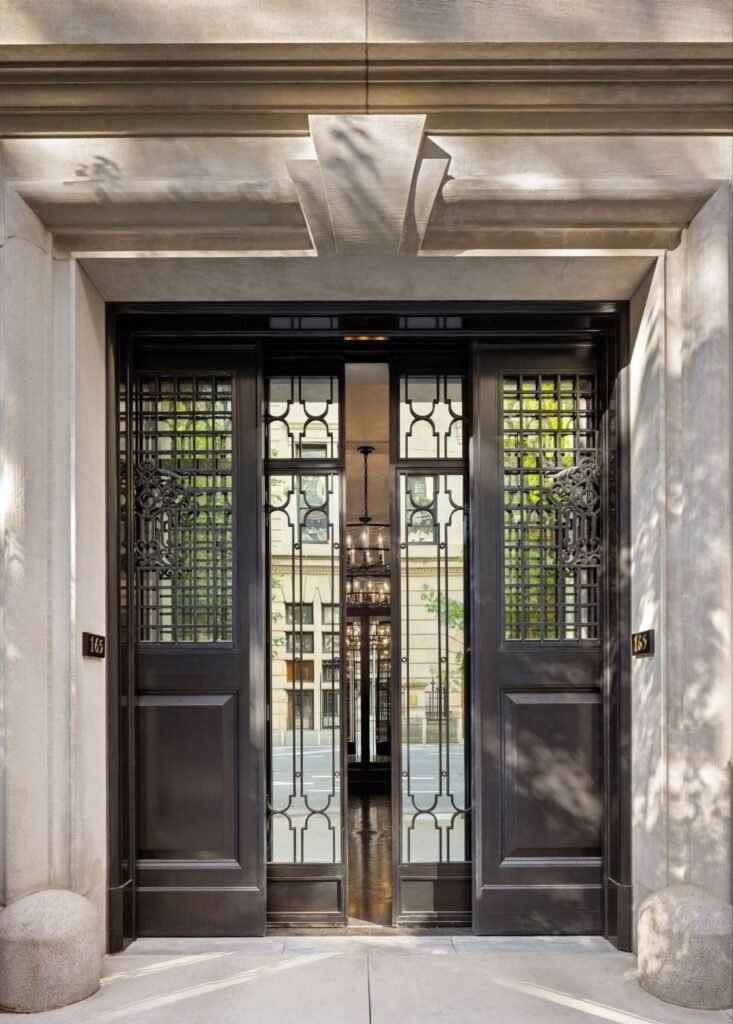 Mirrored Horus bronze doors and limestone entry portal at 165 East 70th Street luxury Gilded Age townhouse on the Upper East Side.