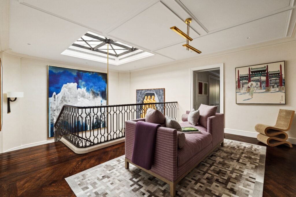Upper landing with a wrought iron and limestone staircase rising 46 feet toward a large skylight at 165 East 70th Street townhouse.