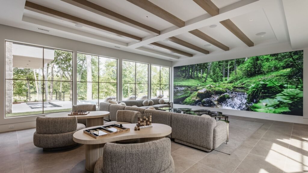 Luxury lower-level entertainment lounge at "The Reverie" estate in Zionsville, Indiana, featuring a 20-foot media wall, coffered beam ceilings, and custom game tables