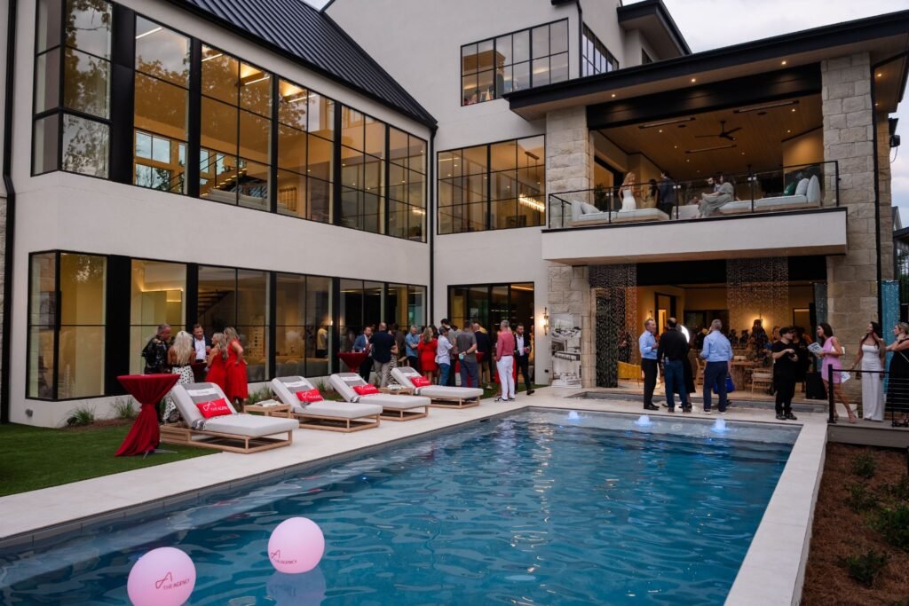 The Agency's "Red Poolside" Cocktail Party at "The Reverie" luxury estate in Zionsville, Indiana, with guests mingling by the illuminated swimming pool