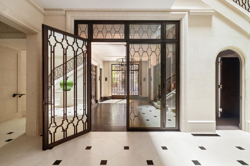 Honed Beauvallon limestone foyer and custom bronze glass doors inside 165 East 70th Street luxury townhouse entry, Manhattan Upper East Side real estate.