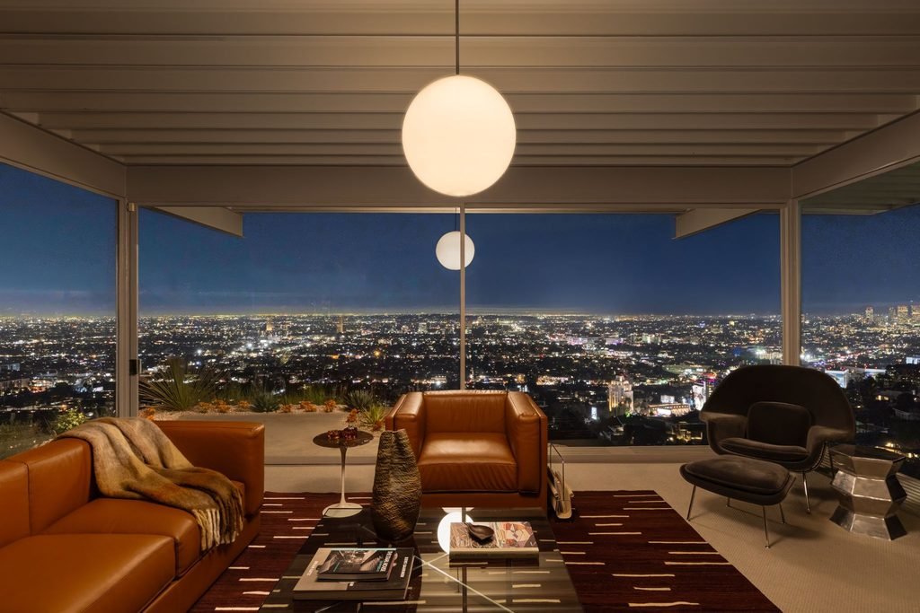 Interior of the Stahl House Case Study House 22 at night featuring mid-century modern furniture and panoramic Los Angeles skyline views through floor-to-ceiling glass walls.